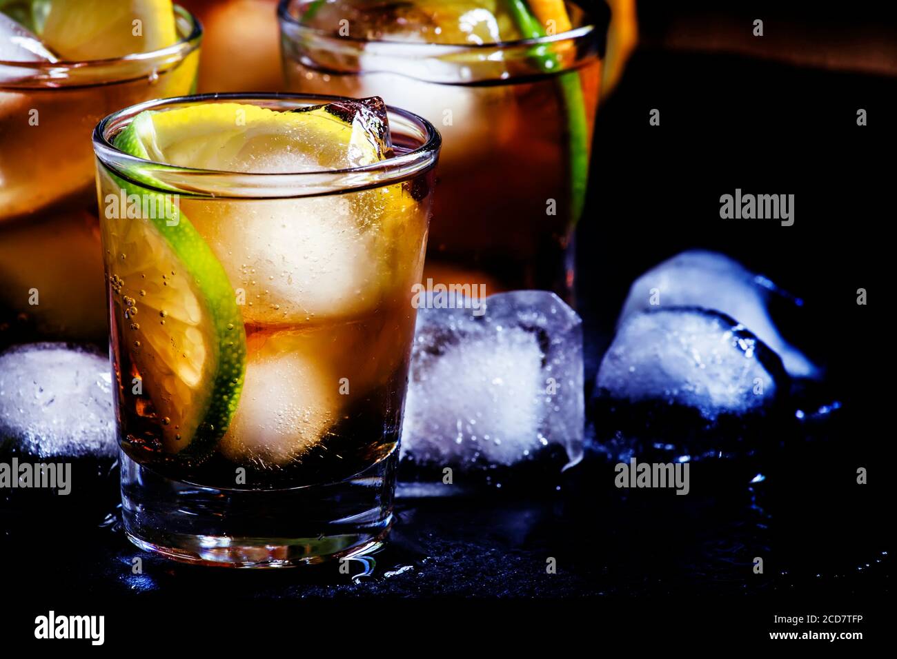 Alcoholic cocktail rum cola with ice, lime, lemon, cola and white rum, dark background, selective focus Stock Photo
