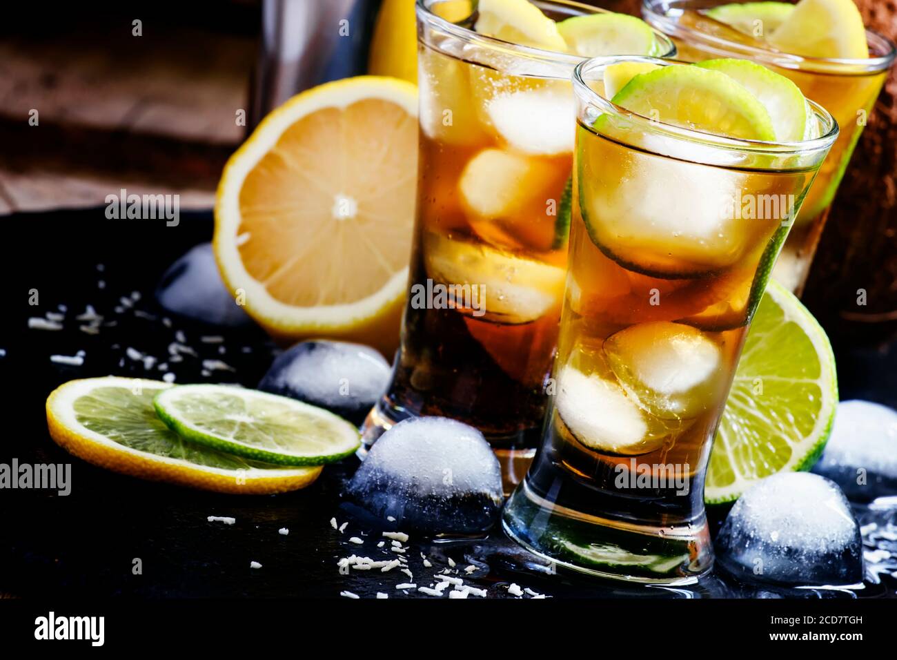 Alcoholic cocktail coconut cola, liqueur, lime, lemon and ice, black background, selective focus Stock Photo