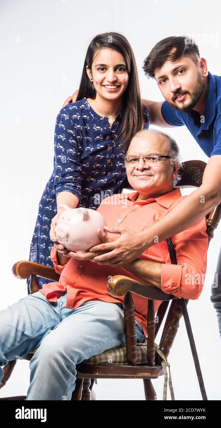 Indian old man or father holding piggy bank with young son and daughter ...