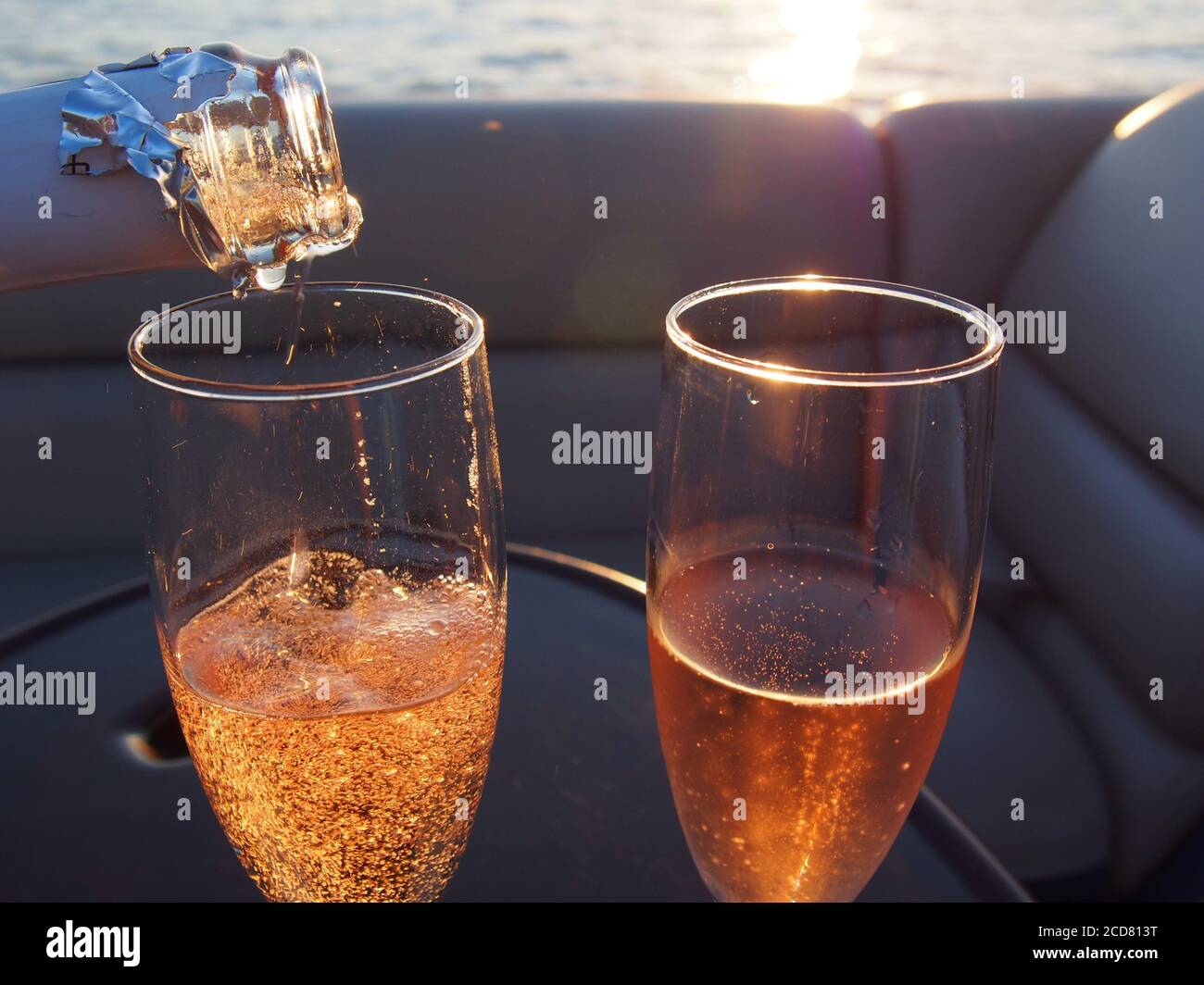A Pair of champagne flutes filled with sparkling rose' at sunset Stock Photo
