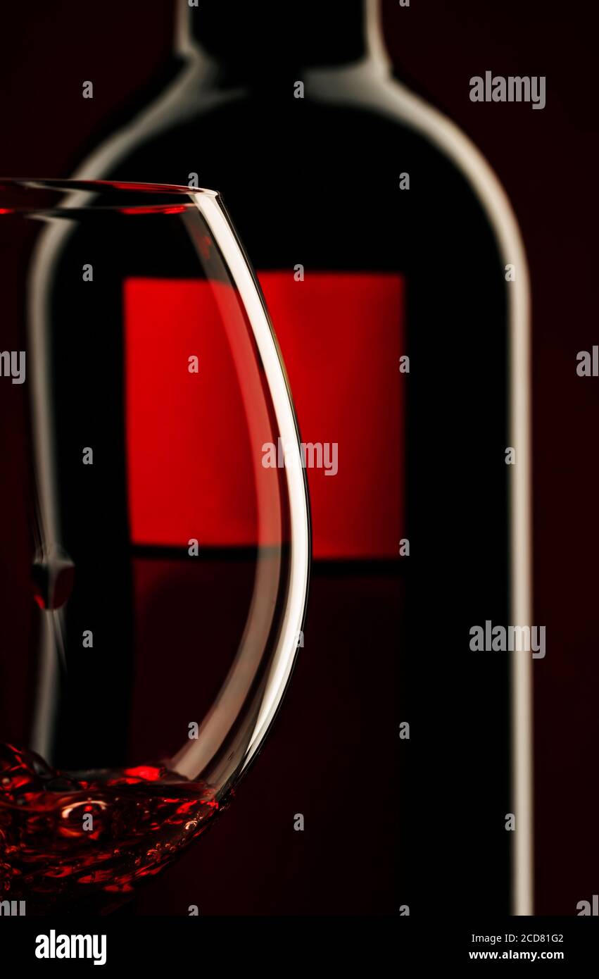 Pouring red wine into the glass against red black background Stock
