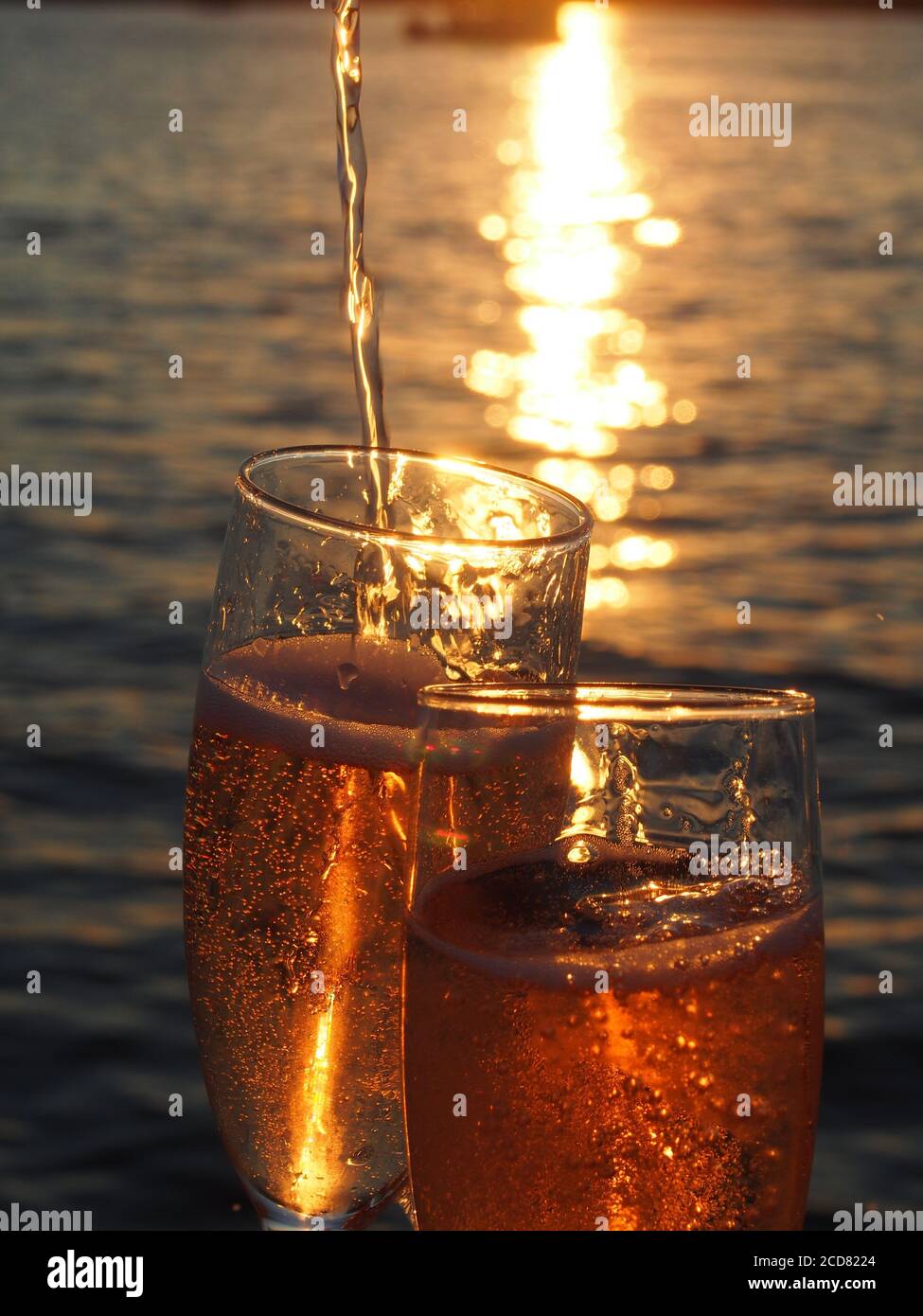A Pair of champagne flutes filled with sparkling rose' at sunset Stock Photo