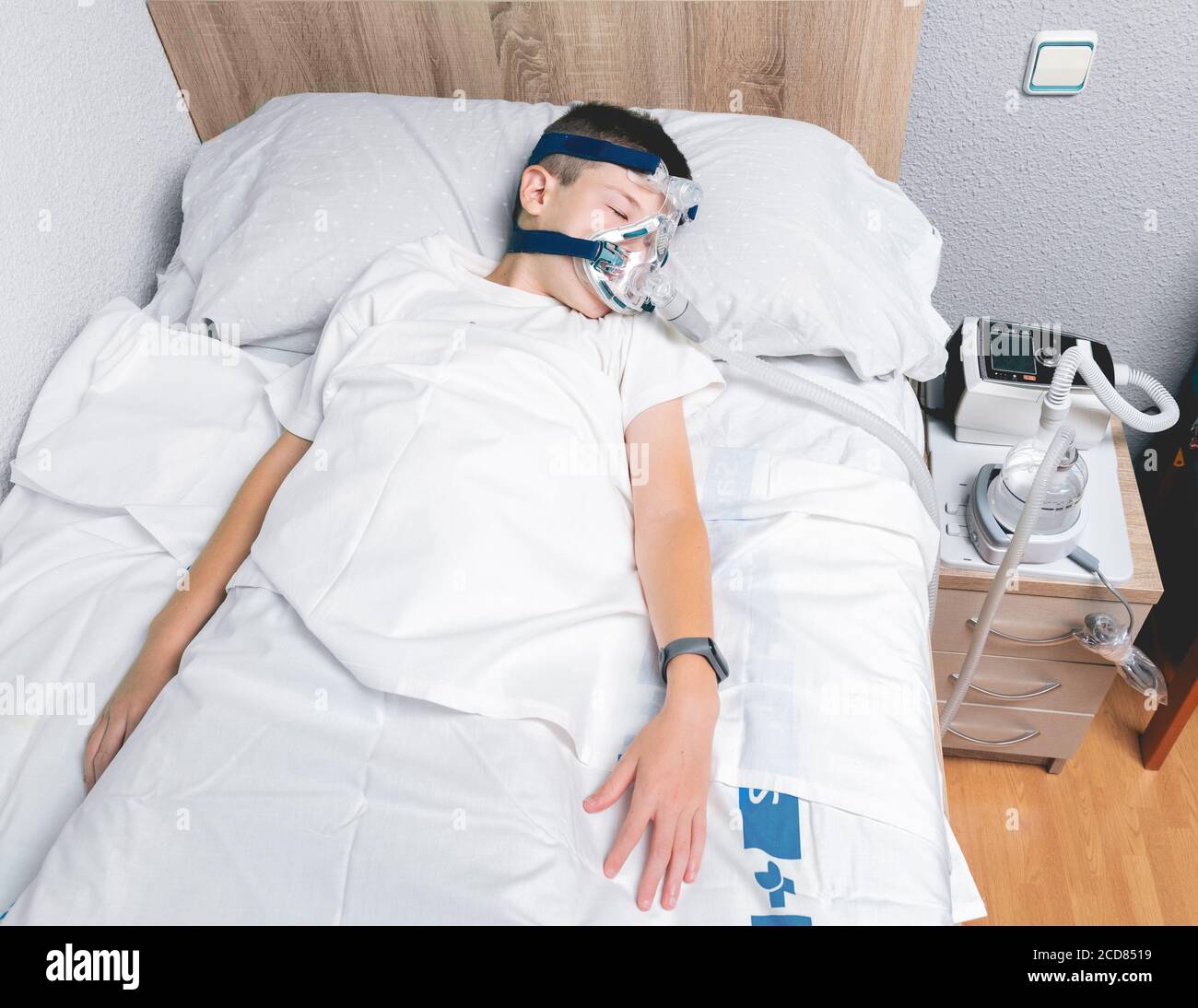 Overhead shot of a child wearing a nebulizer mask sleeping on his