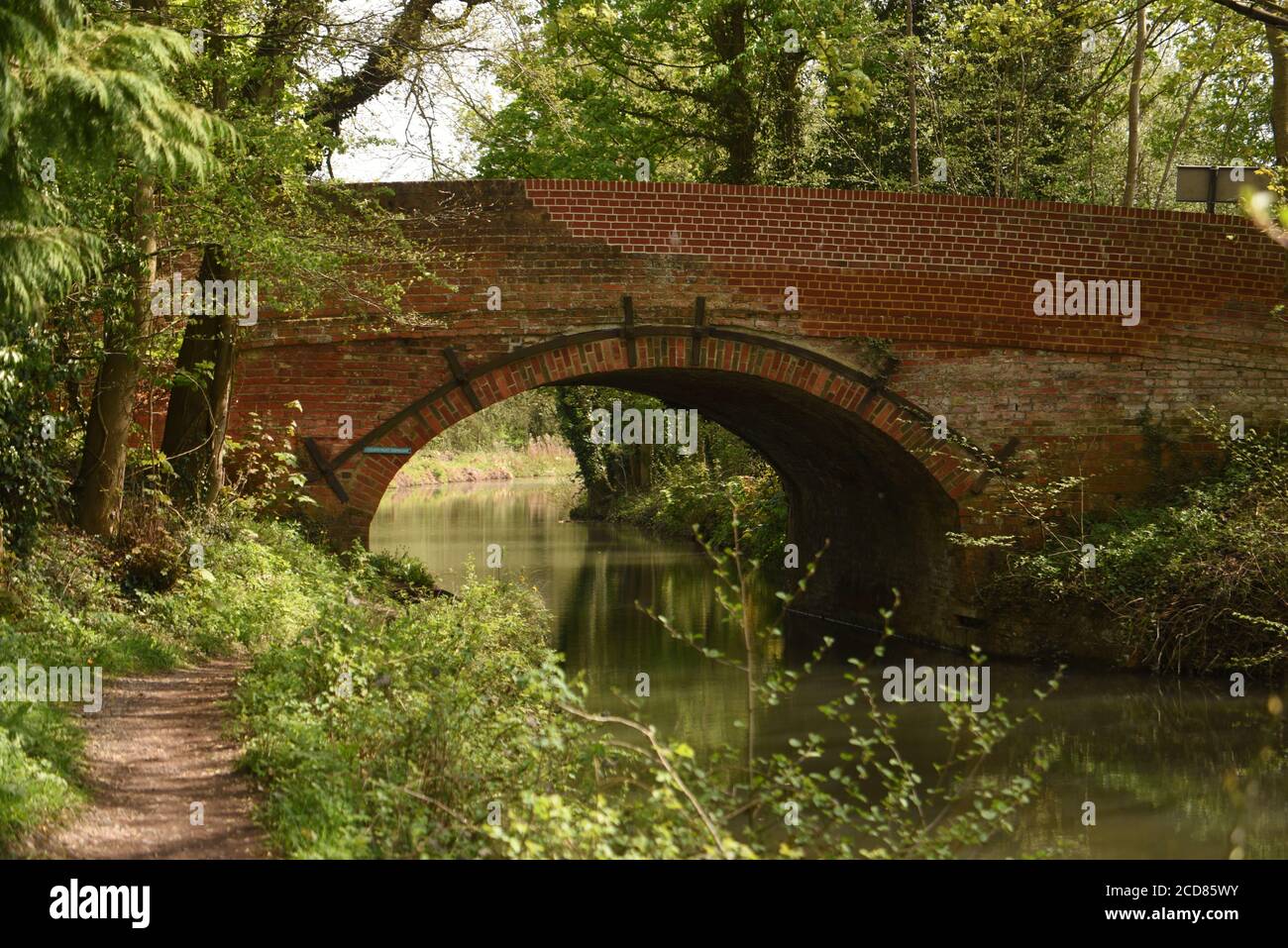 A relaxing scene with a bridge over the calm waters of the Basingtoke Canal in Hampshire, on a beautiful spring day Stock Photo