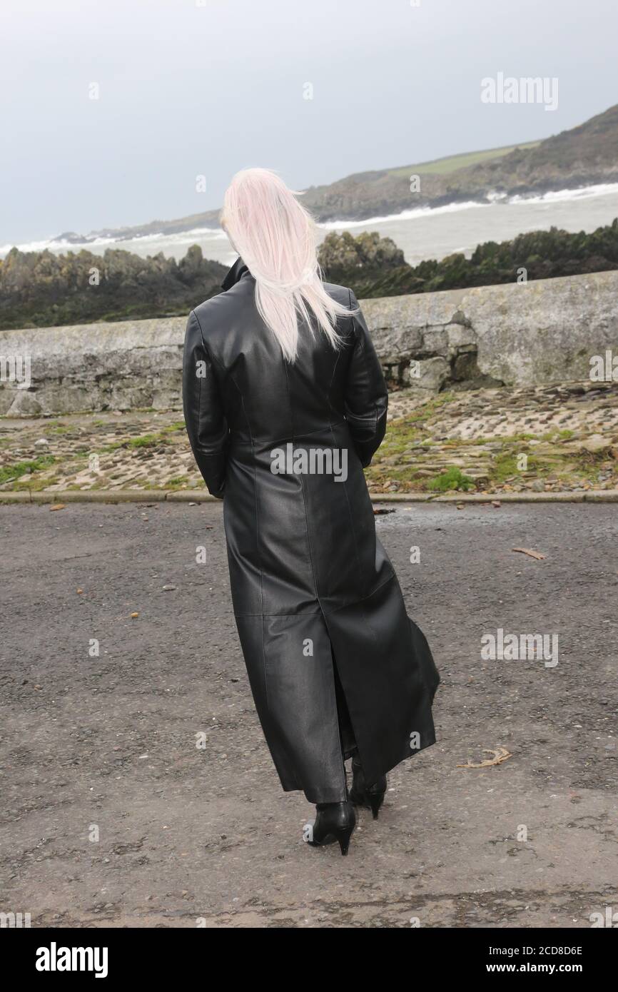Caucasian white middle aged woman in long leather coat collar turned up with dyed hair walking on windy day. Isle of Whithorn Dumfries Galloway Stock Photo Alamy