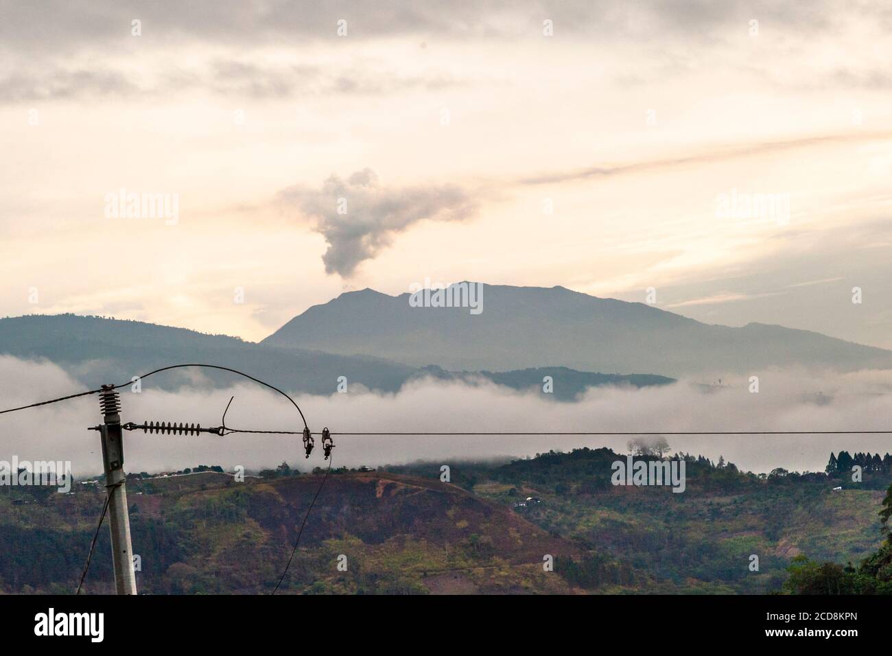 Morning mood with power line in front of a smoking volcano in Costa Rica Stock Photo