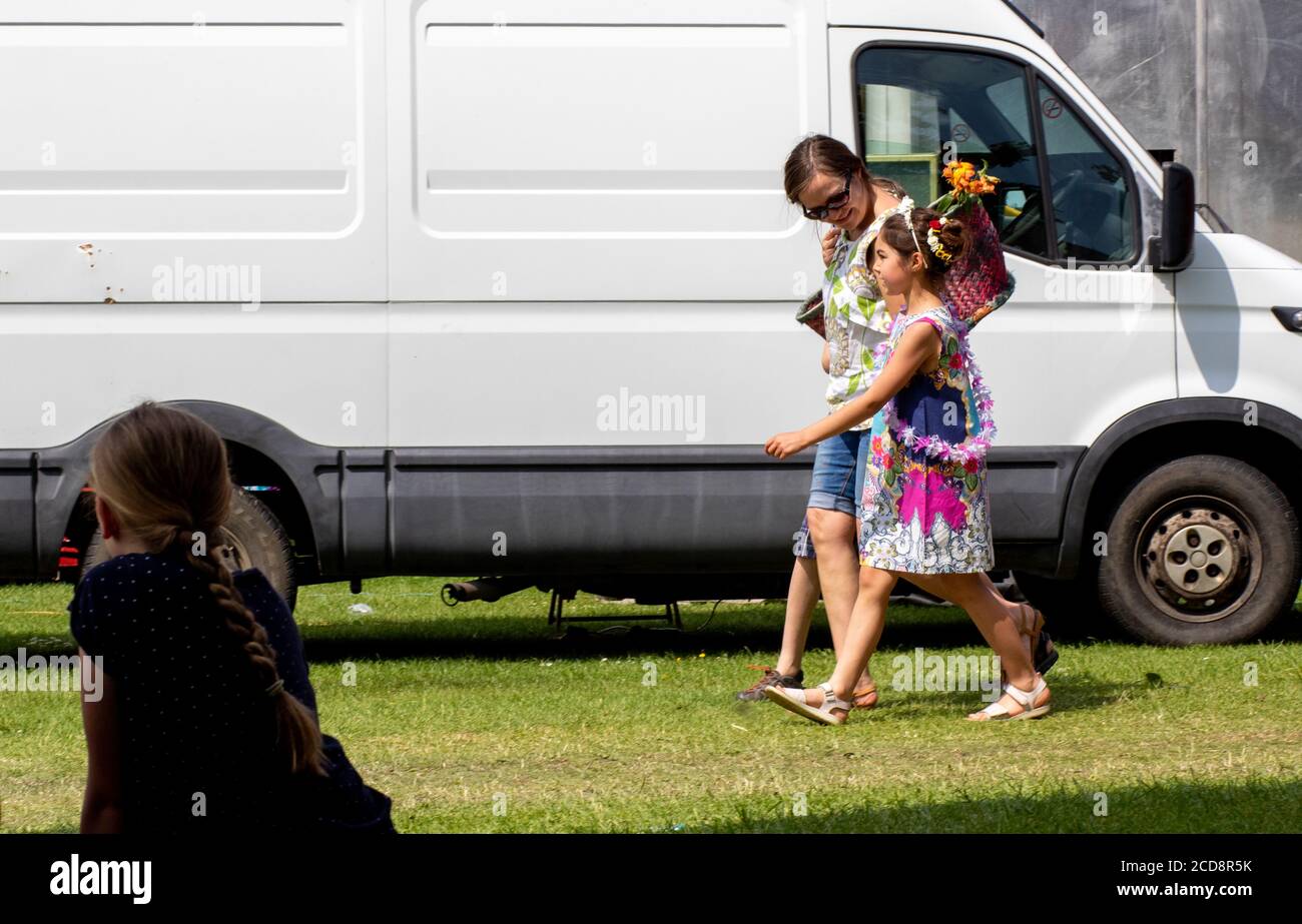 Small family group waking past a white van on a sunny day Stock Photo