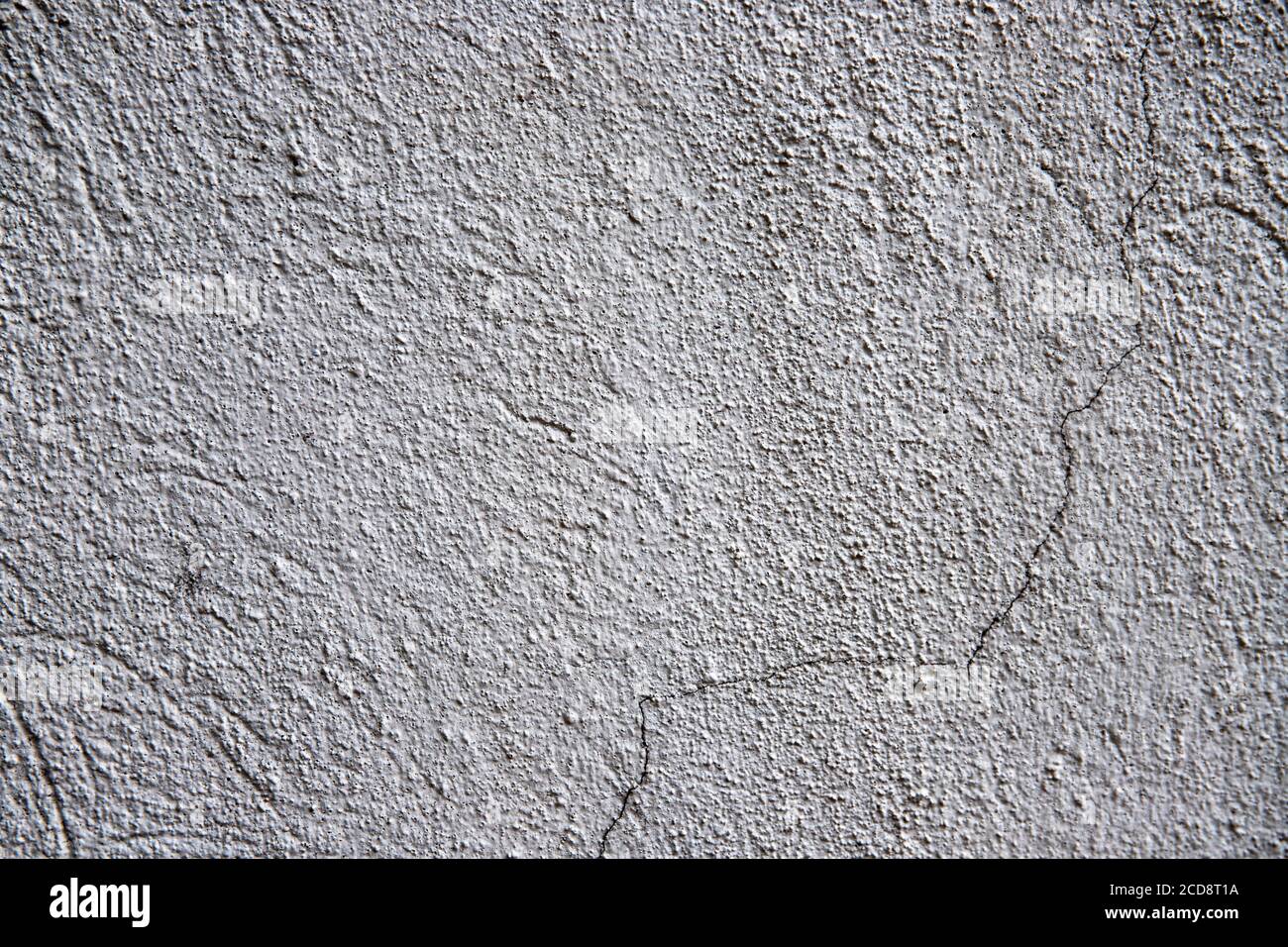White plaster painted wall with grit and cracks. Cracked wall closeup photo. Architecture detail background. Empty concrete wall. Grungy surface of pa Stock Photo