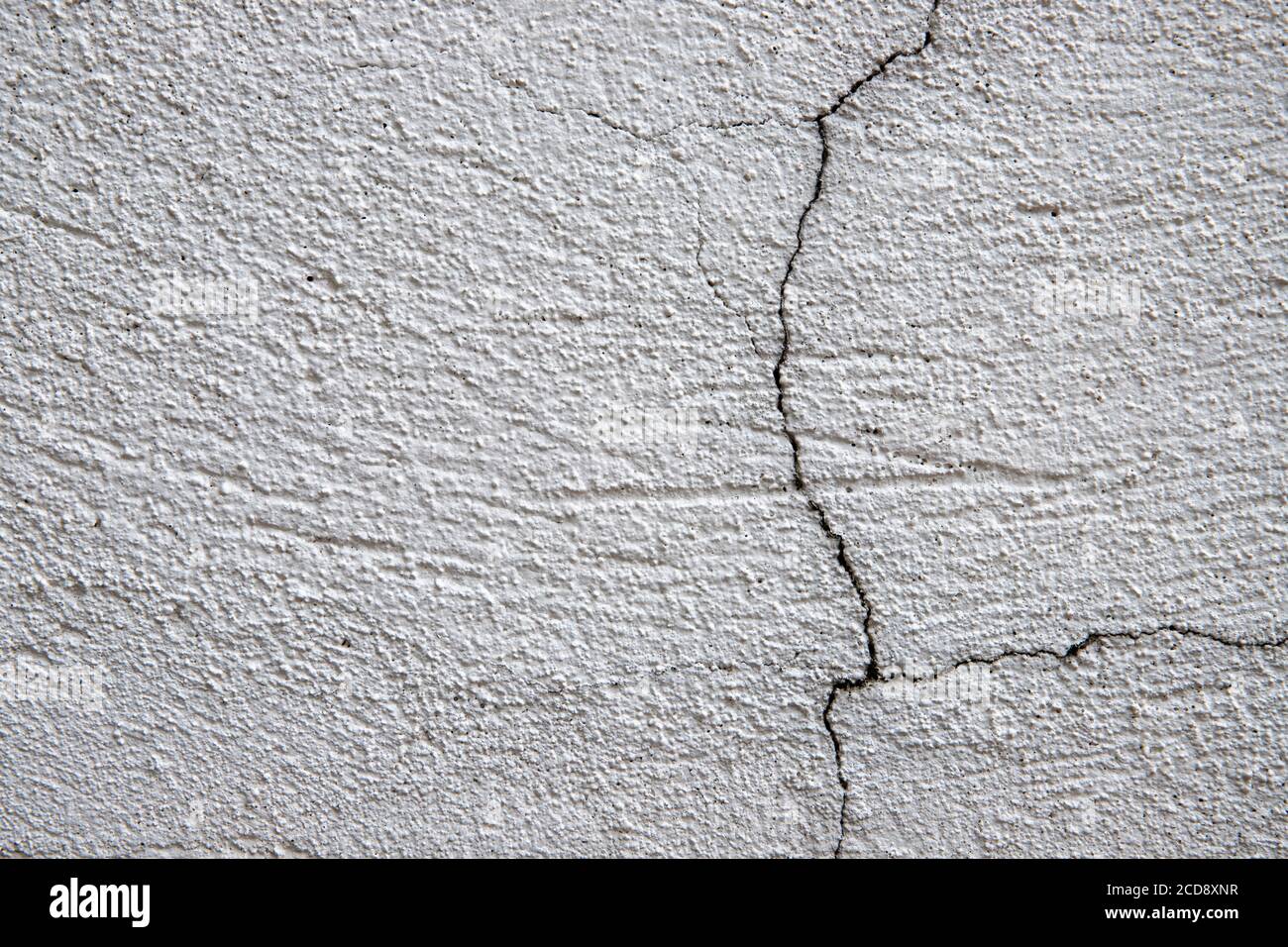 White plaster painted wall with cracks. Cracked wall closeup photo. Architecture detail background. Empty concrete wall. Grungy surface of painted cem Stock Photo