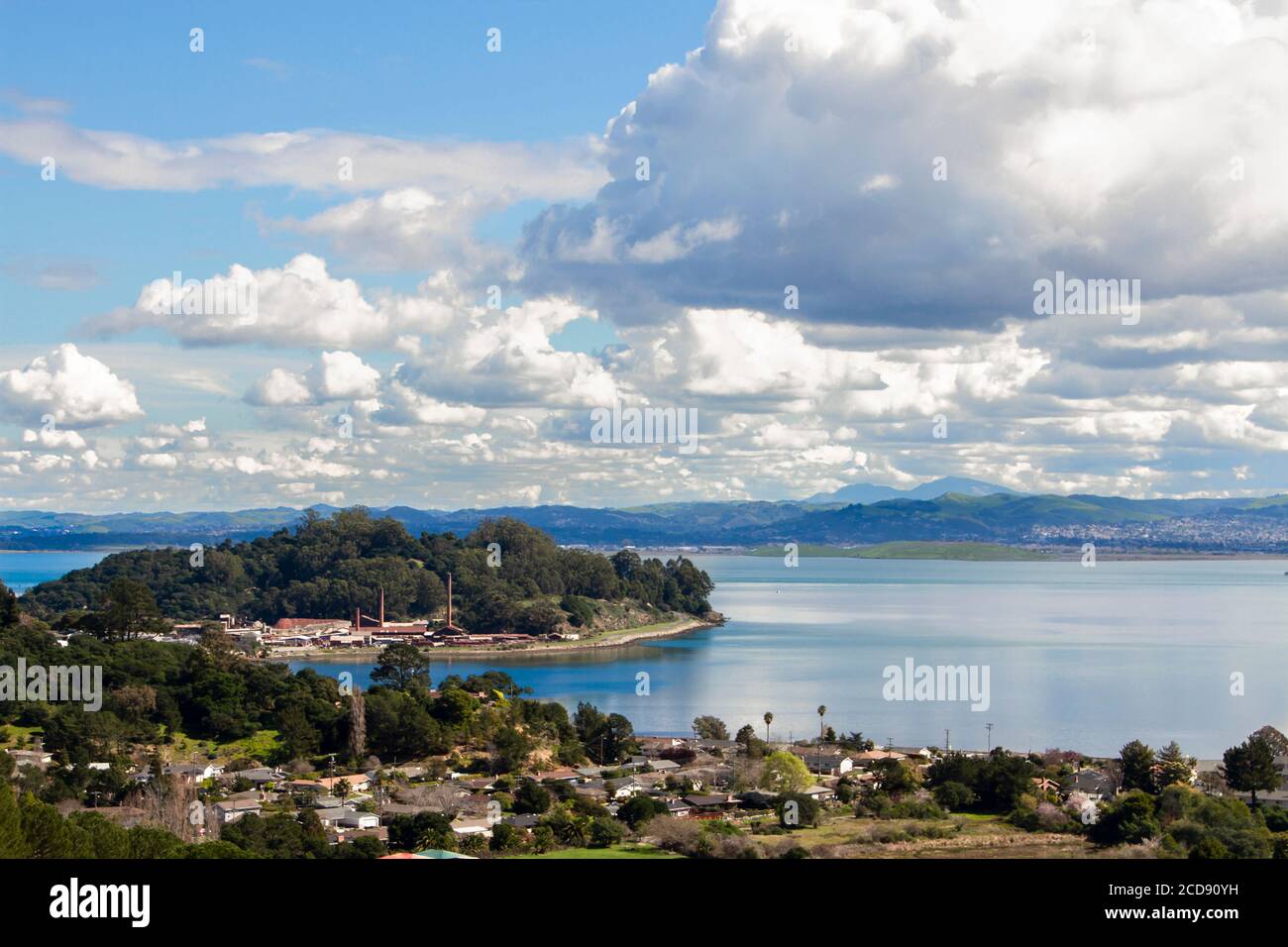 Massive clouds sweep through blue skies over the San Rafael Bay section of San Francisco Bay with neighborhoods, rock quarry and calm blue waters Stock Photo