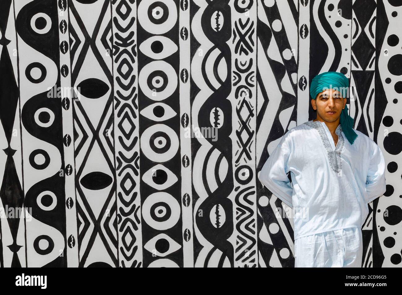 Marocco, Oued Ed-Dahab, Dakhla, Les Dunes Eco-lodge, young Moroccan in traditional clothes in front of a tent decorated with African tribal patterns Stock Photo