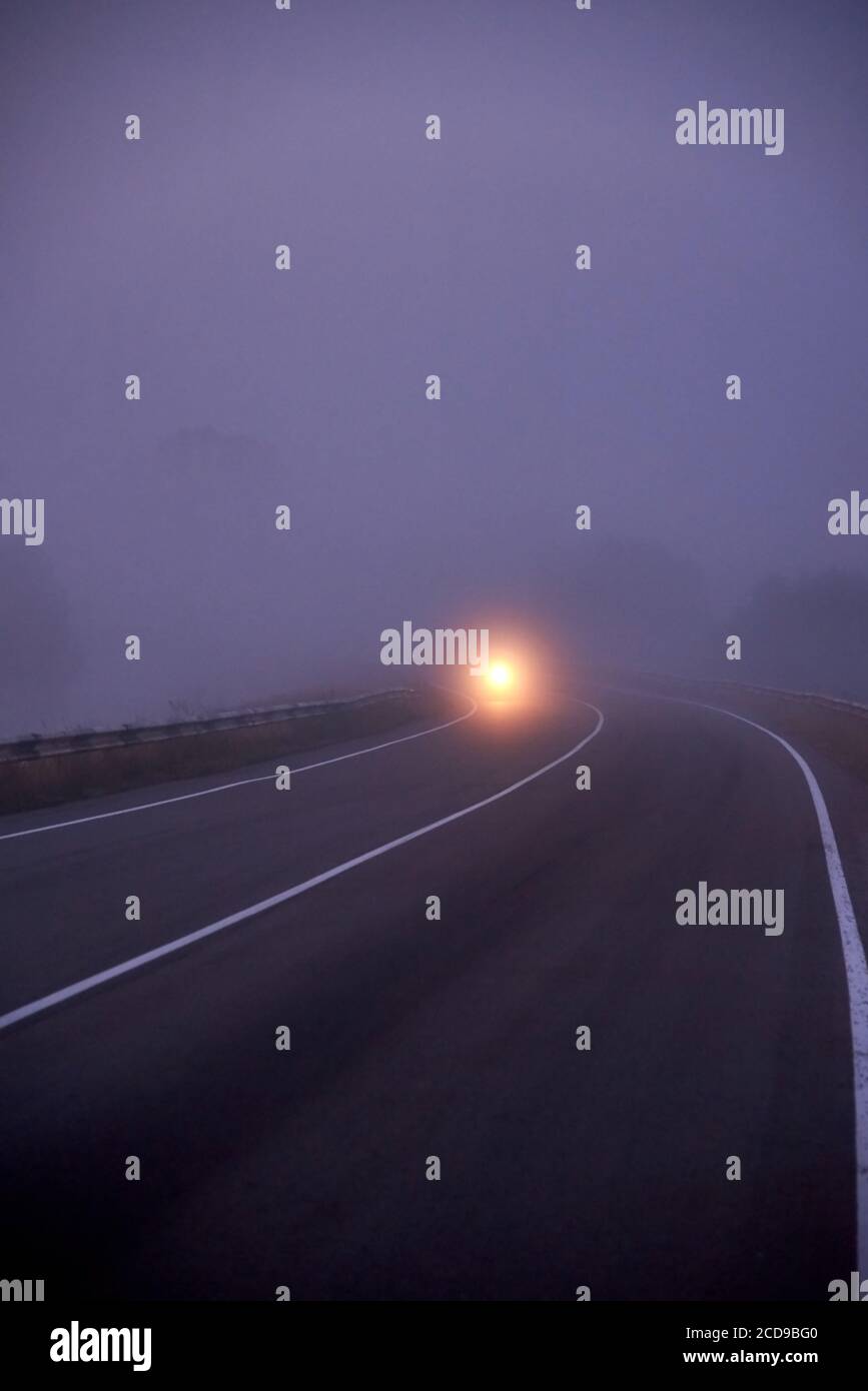 Dense fog on the road in the morning, the light from the headlights of ...