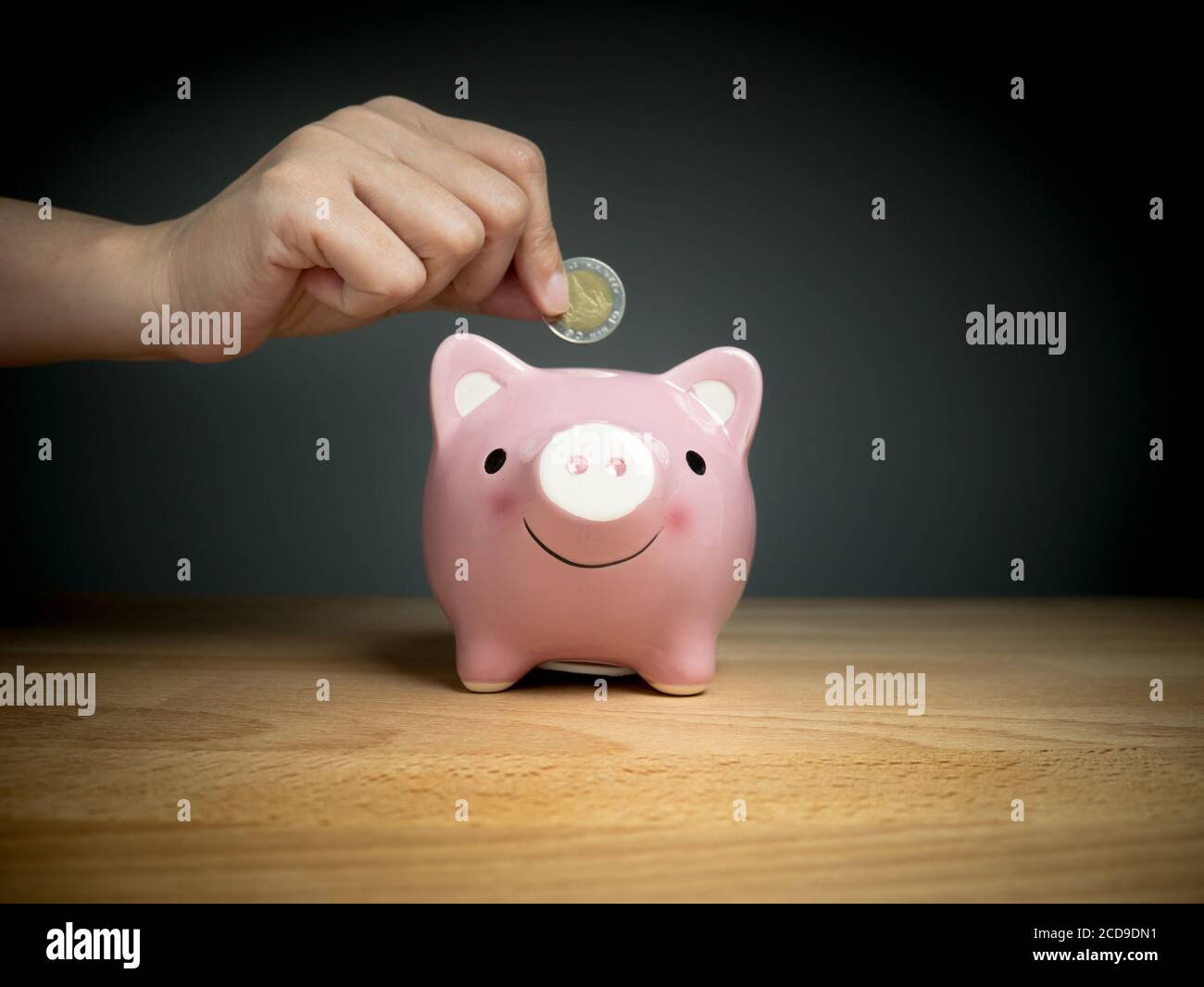 hand add coin to piggy bank save coin, time and money concept. Stock Photo