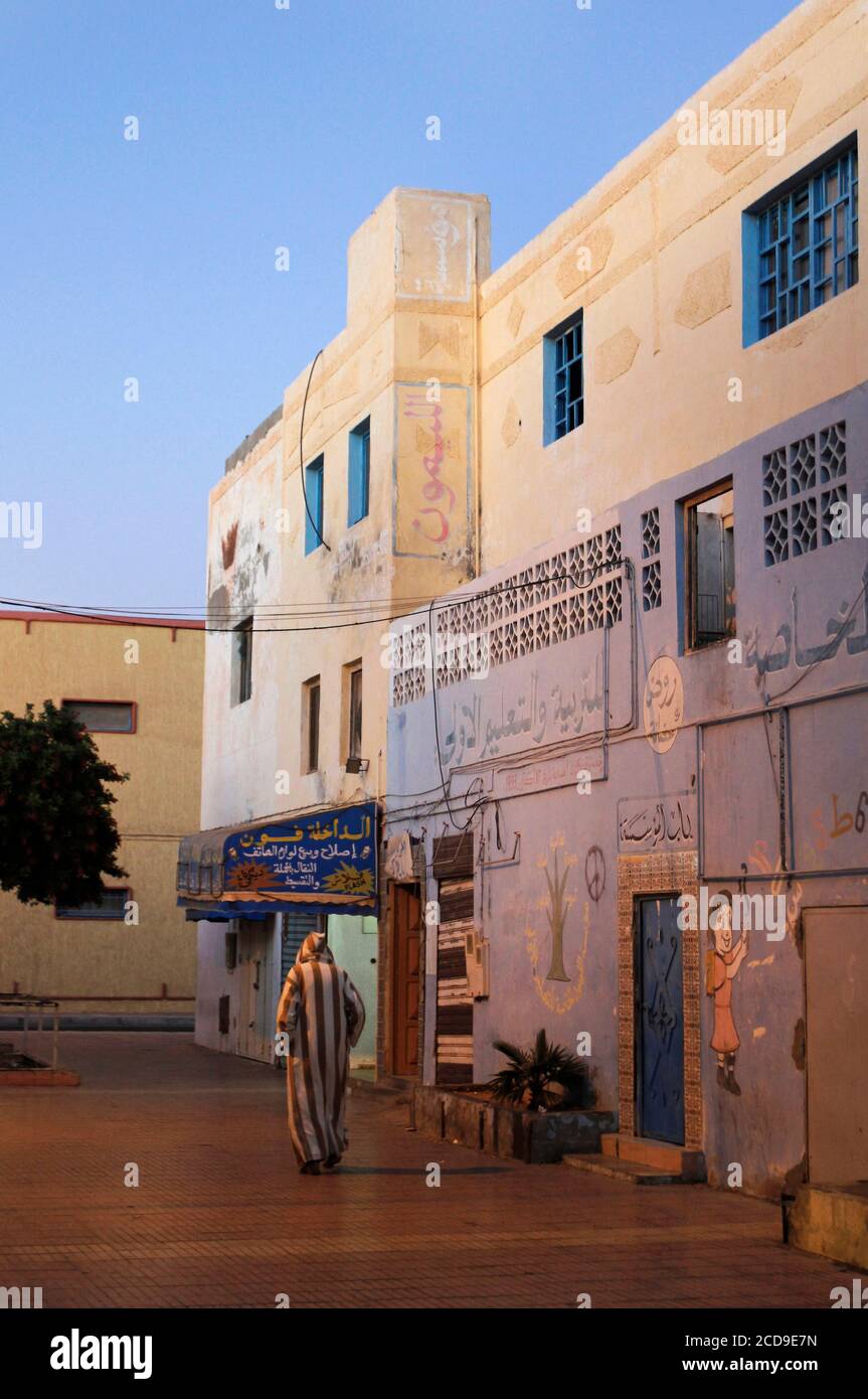 Morocco, Western Sahara, Dakhla, old moroccan djellaba walking in an alley dive into the end of the day light Stock Photo