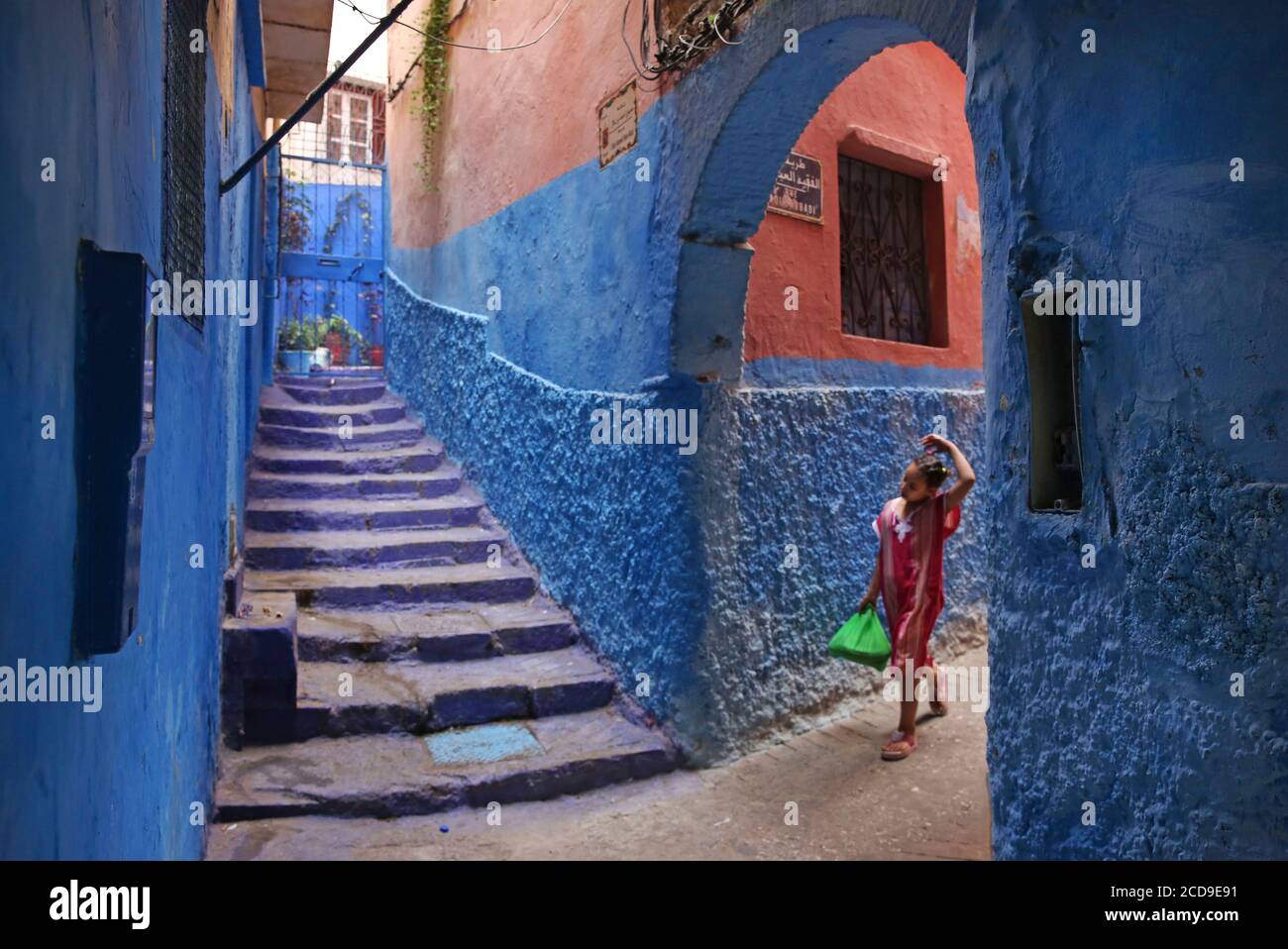Morocco, Tangier Tetouan region, Tangier, Moroccan girl in an alley of the medina with blue walls Stock Photo