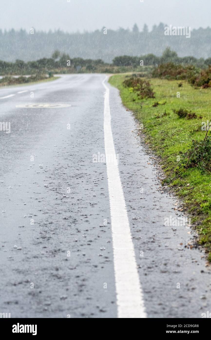 Torrential rain splashing in a flooded roadside during a thunderstorm Stock Photo