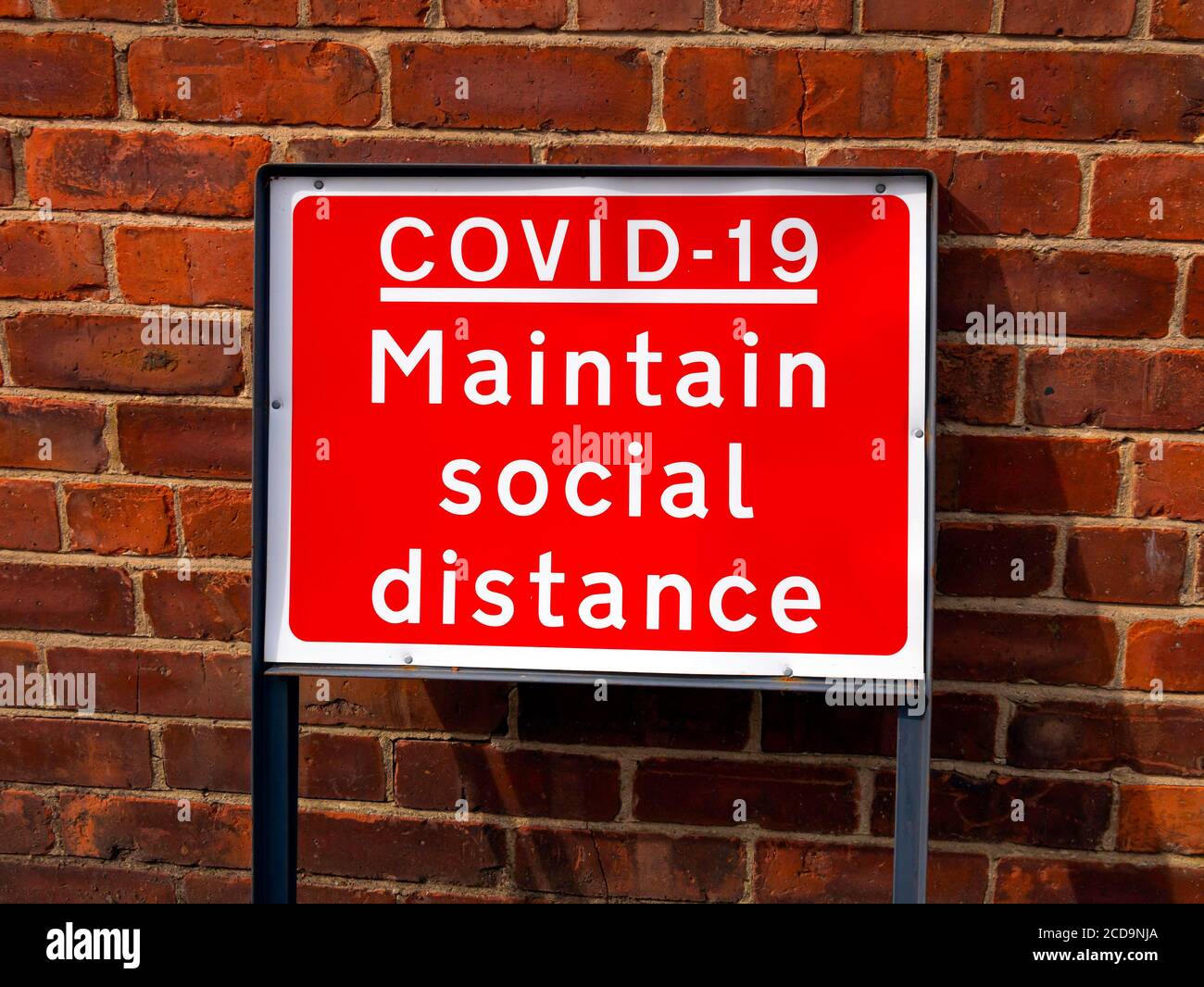 A red street sign Covid 19 Maintain Social Distance Stock Photo