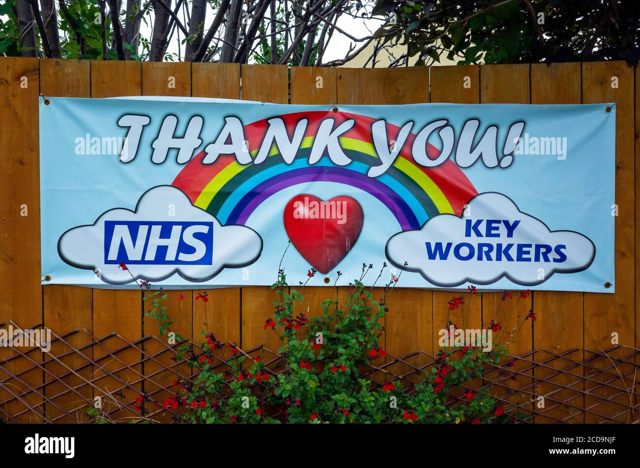 A colourfull notice attached to a garden fence with a rainbow a heart and text Thank You NHS key workers Stock Photo