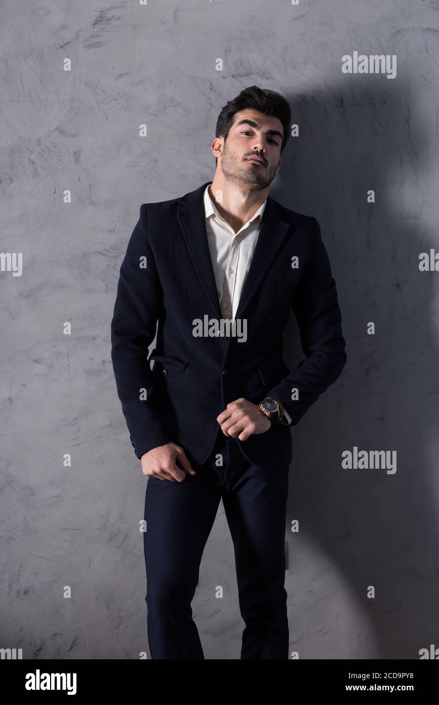 A serious handsome young businessman in a black suit checking the time ...