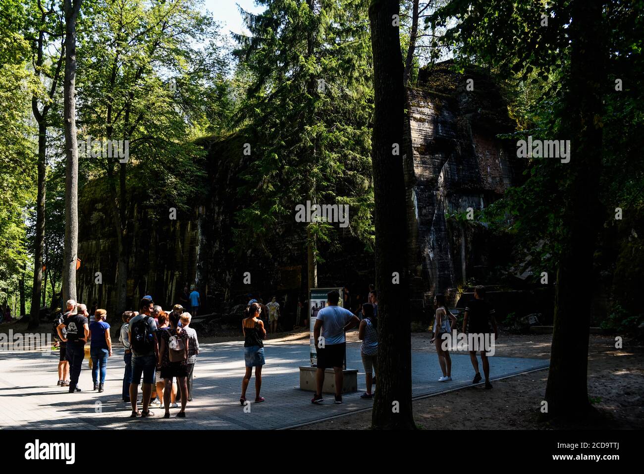 Visitors walk by a destroyed bunker part of the historical Wolf's Lair, the first Hitler' military headquarters on the Eastern front with the objective to start of the Soviet Union, in Gierloz. The famous Wolf's Lair was one of the top secrets headquarters of Nazi Germany located on nowadays Eastern Poland. The nazi site is famous for the assassination attempt on Adolf's Hitler life known as Operation Valkyrie, Claus von Stauffenberg and others targeted Hitler with a suitcase bomb during a meeting inside the Wolf's Lair. Stock Photo