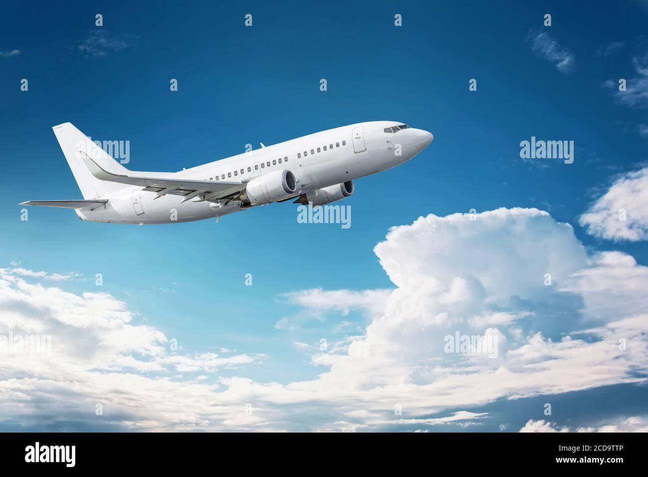 Civil aircraft flying into deep blue skies with some cloud Stock Photo