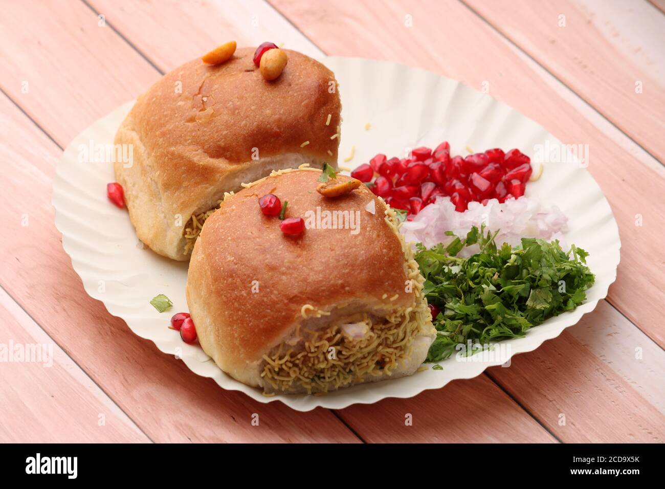 dabeli high resolution stock photography and images alamy https www alamy com dabeli is an indian snack item served with pomegranate seeds and cilantro in white paper plate over wooden background image369626367 html