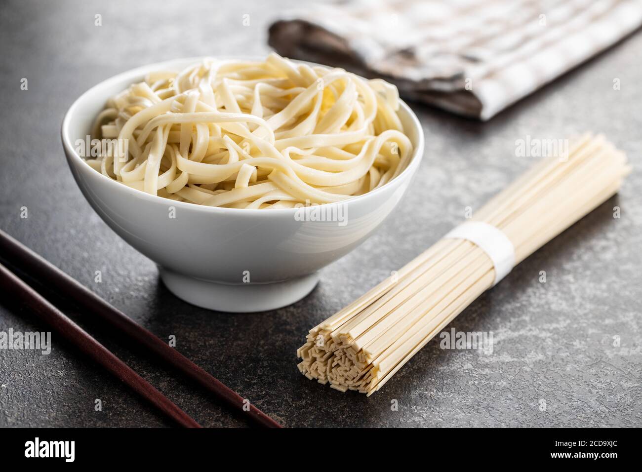 Cooked udon noodles. Traditional Japanese noodles in bowl on black table. Stock Photo