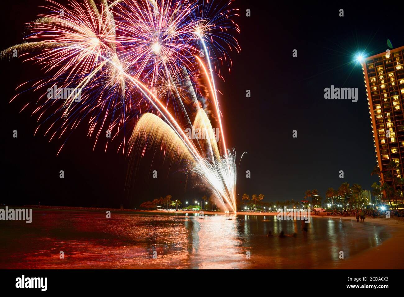 Weekly firework display over touristy beach and waterfront, in front of hotel high rises in the