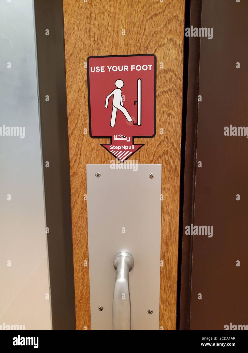 Sign reading Use Your Foot and directing visitors to use a Step N Pull door opener, which allows users to open doors using their feet to avoid contact with public surfaces, Concord, California, July 9, 2020. () Stock Photo
