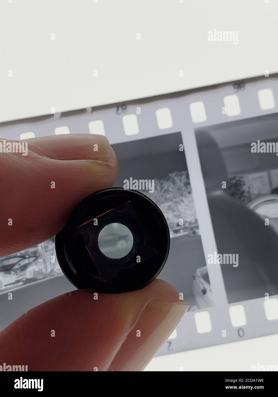 Close-up of human hand of a man using a loupe magnifier to examine a black and white photographic negative on a lightbox , July 19, 2020. () Stock Photo