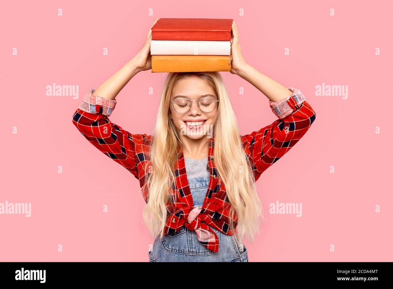 Little girl smiling wide, holding books over head Stock Photo - Alamy