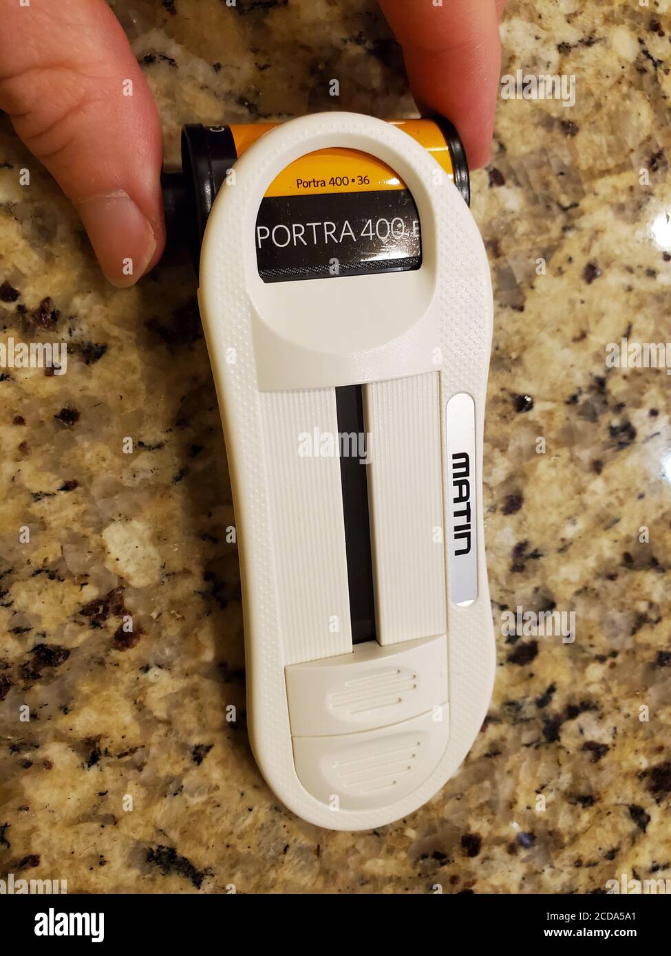 Close-up of human hand using Matin film leader retriver tool to remove the leader from a canister of 35mm camera film, San Ramon, California, August 20, 2020. () Stock Photo