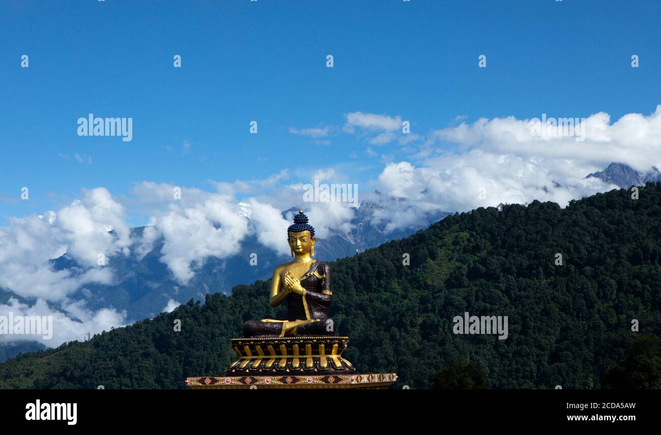 A huge statue of Lord Buddha in a sunny morning in Buddha Park with The Kanchenjunga snow peak in background in Sikkim in India Stock Photo