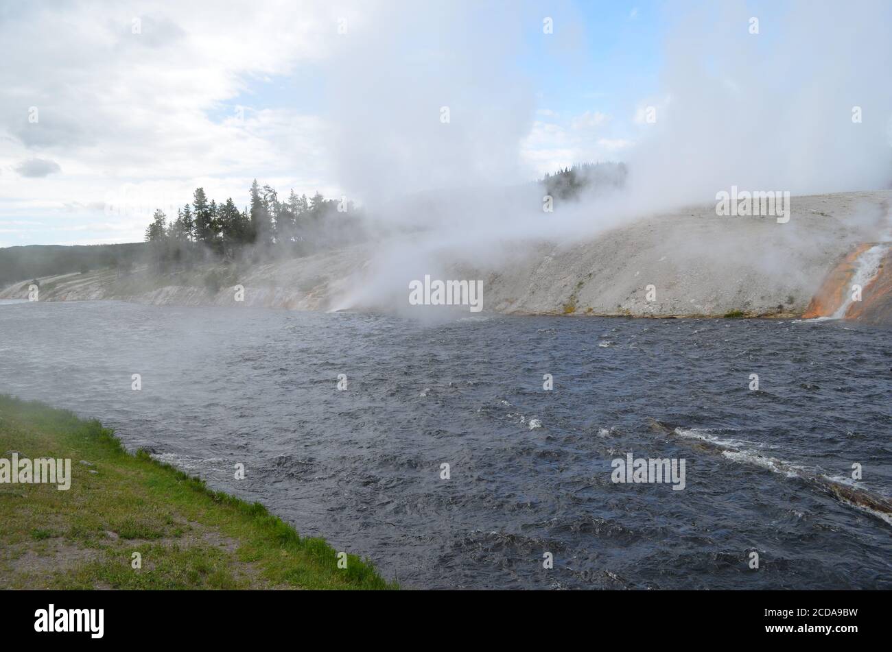 Late Spring in Yellowstone National Park: Steam Rolls Off Excelsior Geyser Crater Next to Firehole River in Midway Geyser Basin Stock Photo