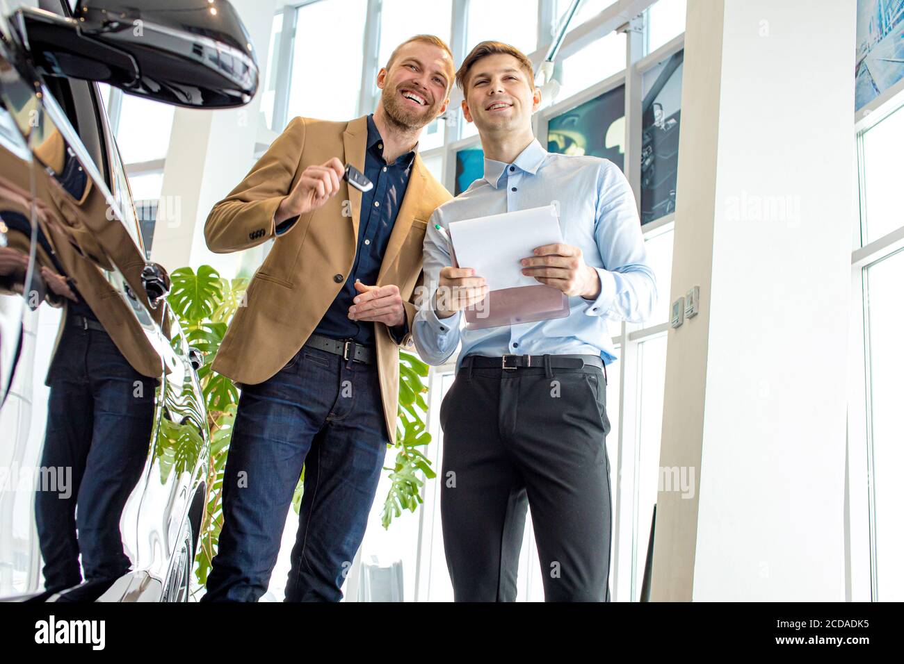 handsome young caucasian cars salesman help customer with choose. man