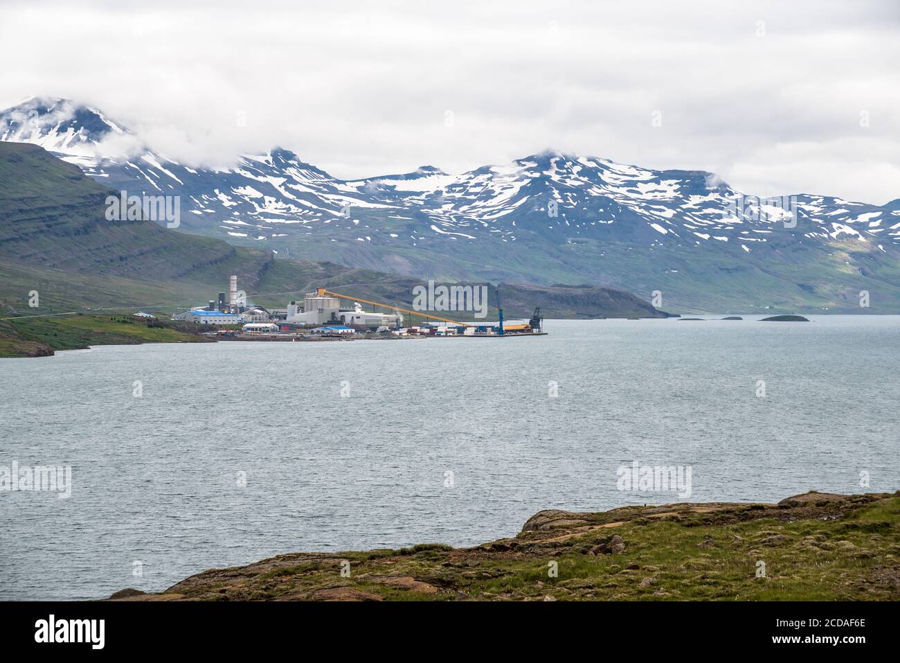 Manufactoring plant on the coast of fjord in Eastern Iceland on a cloudy summer day Stock Photo