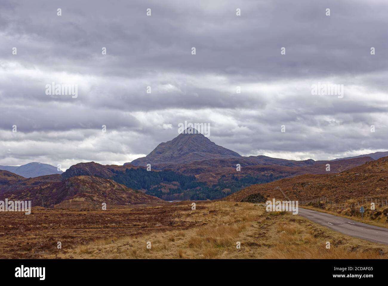 Dramatic Mountain Scenery on the road through the North West Highland Global Geopark in Assynt, with a triangular peak in the background. Stock Photo