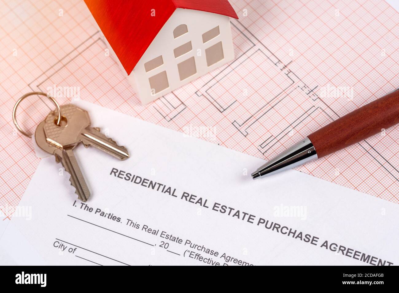 Keys, house model and a pen lying on a real estate purchase contract and a floor plan. Rreal estate purchase concept. Stock Photo