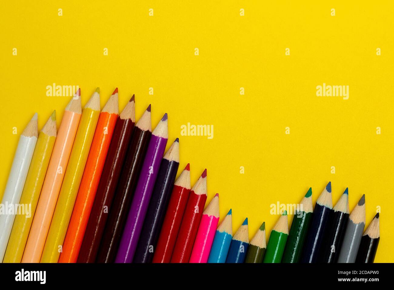 Overhead view of colorful pencils on yellow backdrop. Poster design idea is.  Stock Photo