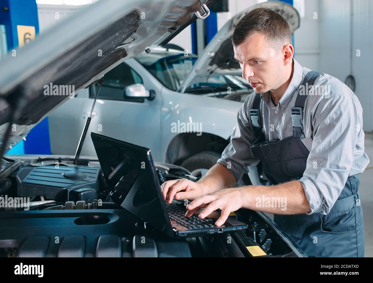 car mechanic using a computer laptop to diagnosing and checking up on