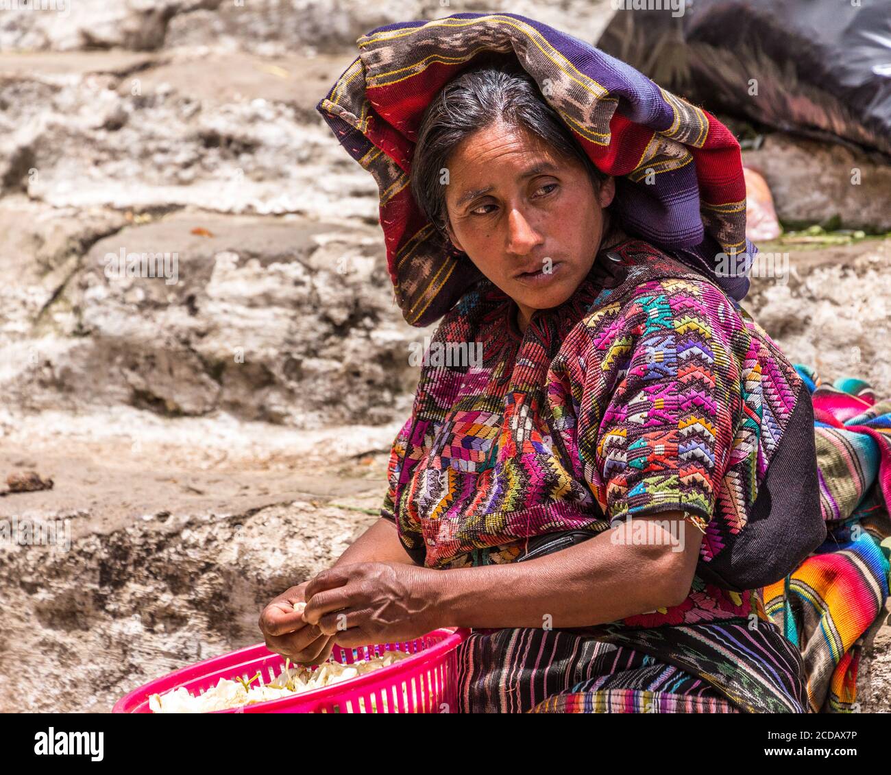 A Quiche Mayan woman in traditional dress sells flower petals  in the market on the pre-Hispanic Mayan steps of the Church of Santo Tomas in Chichicas Stock Photo