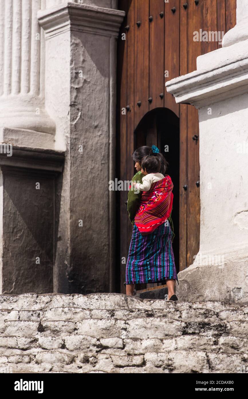 A young Quiche Mayan woman, in traditional dress, and her daughter walk toward the door of the Church of Santo Tomas in Chichicastenango, Guatemala. Stock Photo
