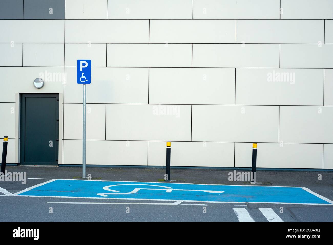 Empty disabled handicap parking space bay with blue marking and handicapped sign symbol by wall. Stock Photo