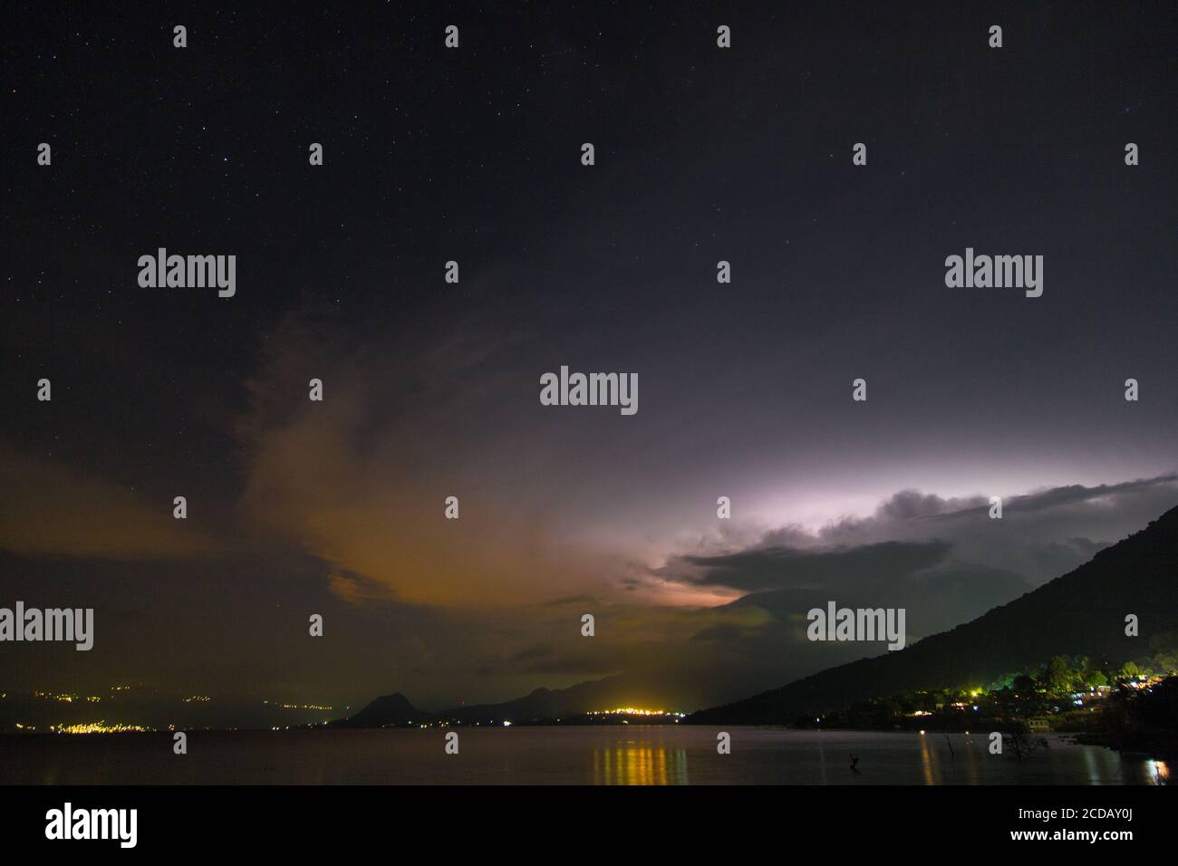 A lightning storm in the clouds over Toliman Volcano at night on Lake Atitlan, Guatemala.  Lake Atitlan is an ancient volcanic caldera or crater, fill Stock Photo