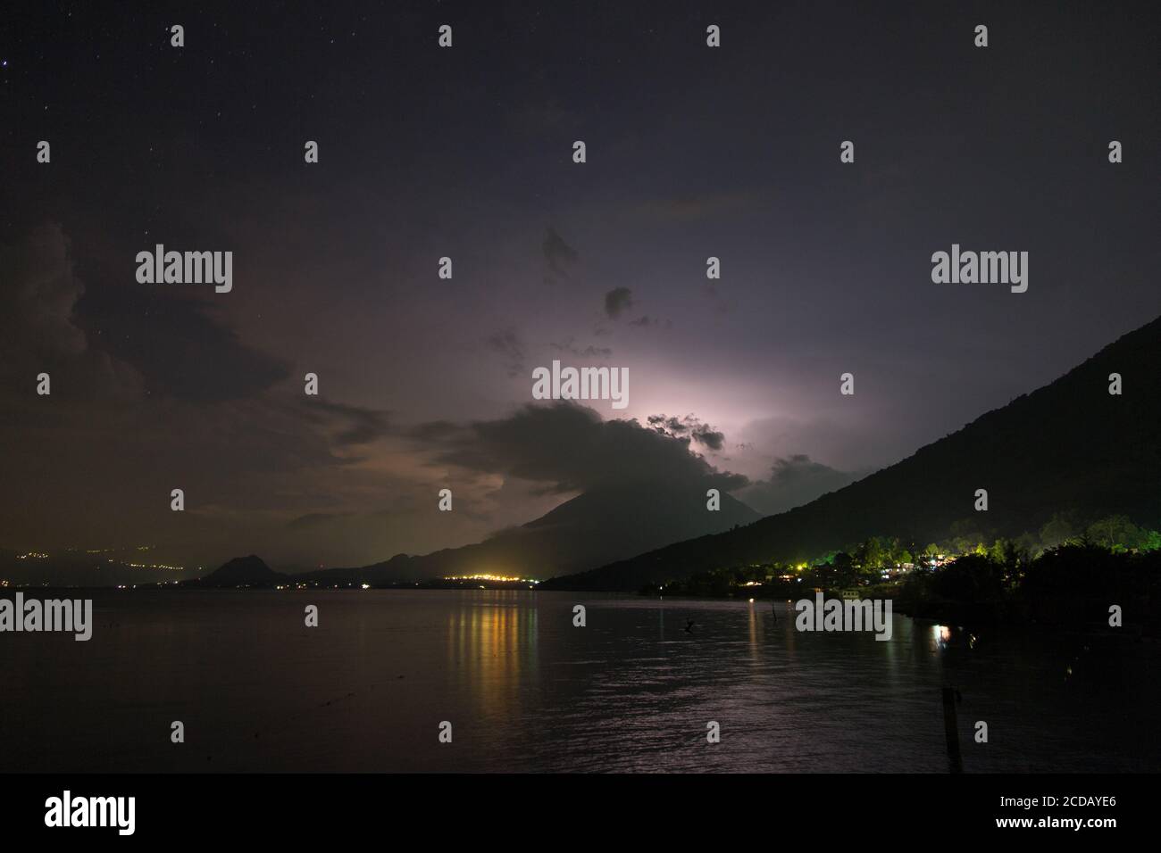 A lightning storm in the clouds over Toliman Volcano at night on Lake Atitlan, Guatemala.  Lake Atitlan is an ancient volcanic caldera or crater, fill Stock Photo