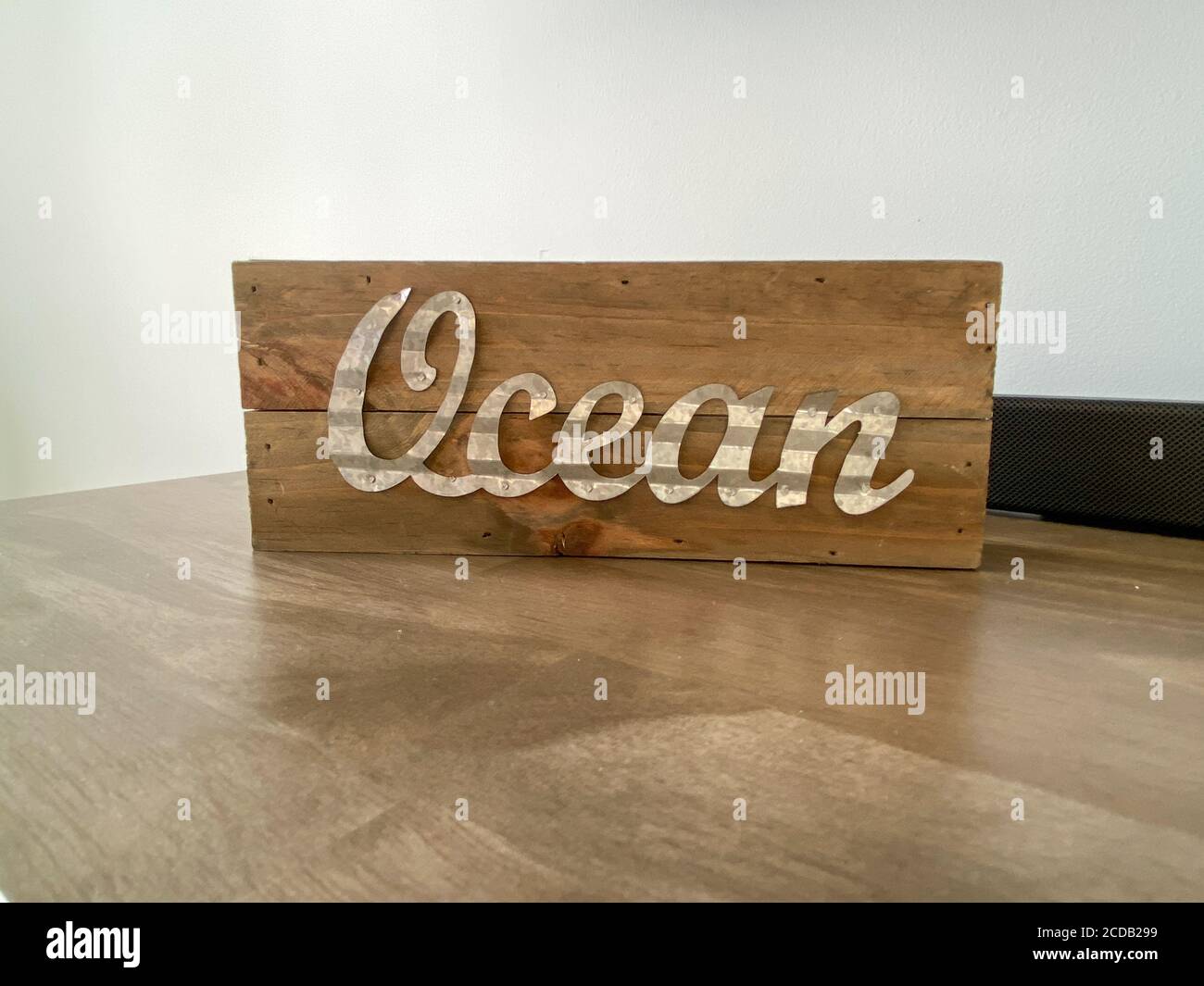 A wooden beach decoration on a table with the word ocean in cursive writing. Stock Photo