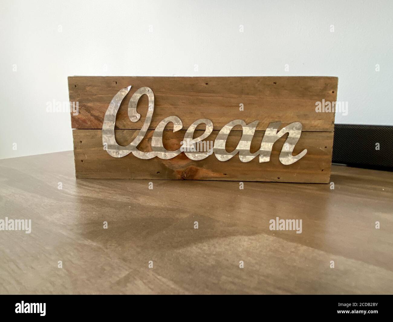 A wooden beach decoration on a table with the word ocean in cursive writing. Stock Photo