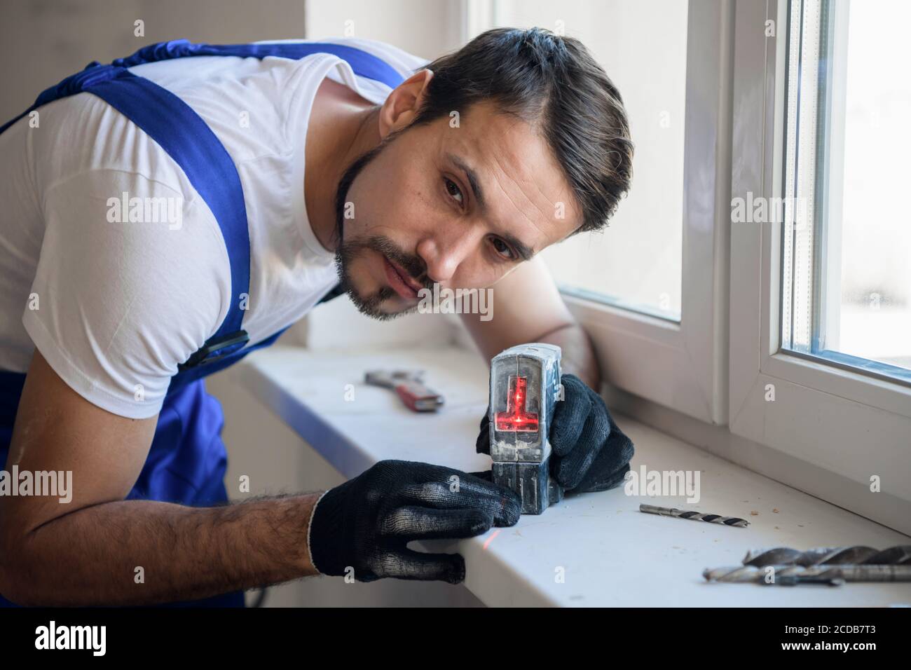 The builder measures the distance from the window with a level Stock Photo