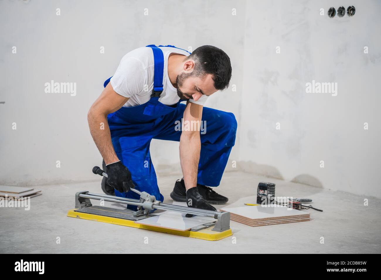Young repairer cuts tiles with a special tool Stock Photo