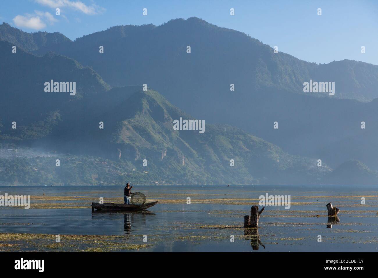 A Mayan fisherman with his wire fishtrap in his cayuco or canoe on Lake Atitlan by San Pedro la Laguna, Guatemala.  Rising lake waters since 2009 have Stock Photo